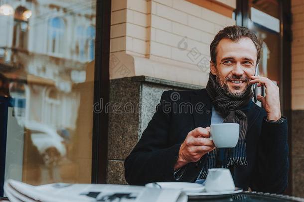 快乐的时髦的男人是（be的三单形式<strong>传达</strong>向smartph向e采用咖啡馆