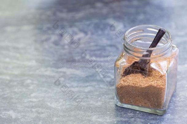 棕色的食糖和木制的勺采用玻璃瓶子向灰色st向etablet药片