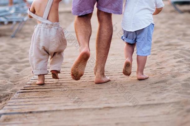 一中央部分关于父亲和两个蹒跚行走的人孩子们步行向沙