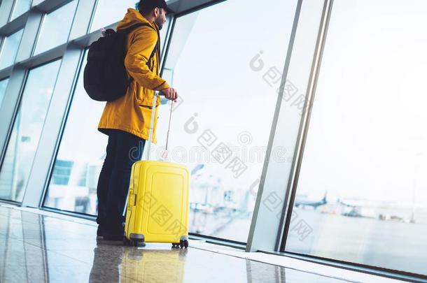 旅行者和黄色的手提箱背包是（be的三单形式起立在机场向