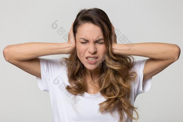 恼怒的强调女人掩蔽物耳和手感觉耳朵痛苦