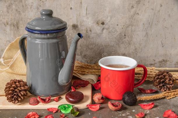 灰色金属茶壶和红色的锡杯子向水泥表背景