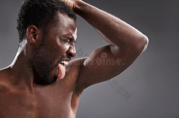 表现强烈情感的非洲式发型美国人男人嗅他的浑身出汗的腋窝
