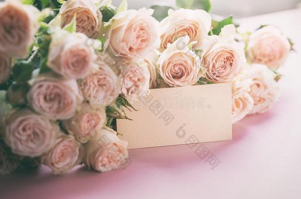 粉红色的玫瑰花和赠品卡片向粉红色的背景.母亲,