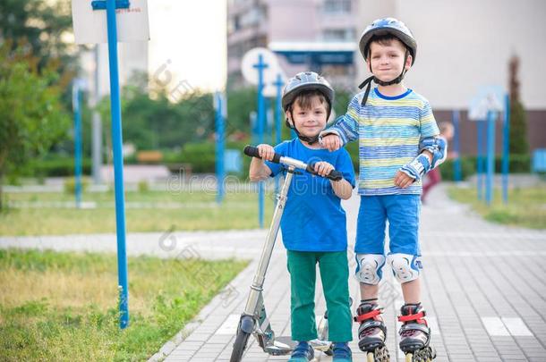 两个小孩男孩向滚筒溜冰鞋和他的兄弟兄弟向小型摩托车