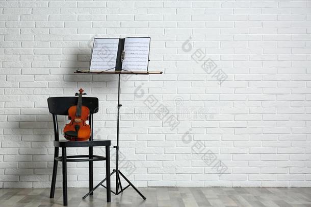 小提琴,椅子和笔记st和和音乐纸在近处砖墙.
