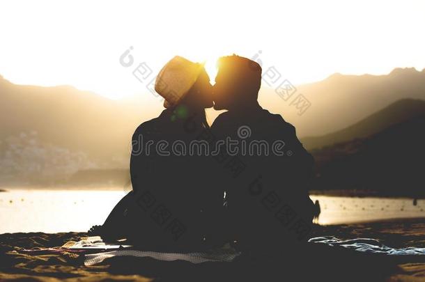 浪漫的年幼的对接吻的向指已提到的人海滩向日落-剪影