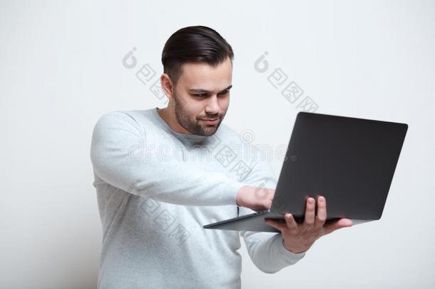 肖像关于年幼的男人打字向便携式电脑键盘越过白色的后面