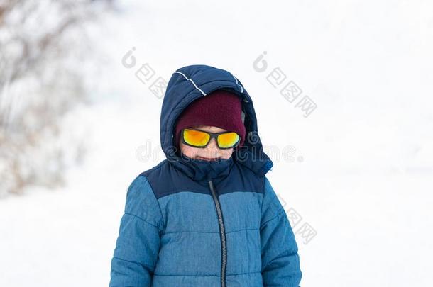 一男孩采用太阳镜和一蓝色j一cket向一下雪的斜坡