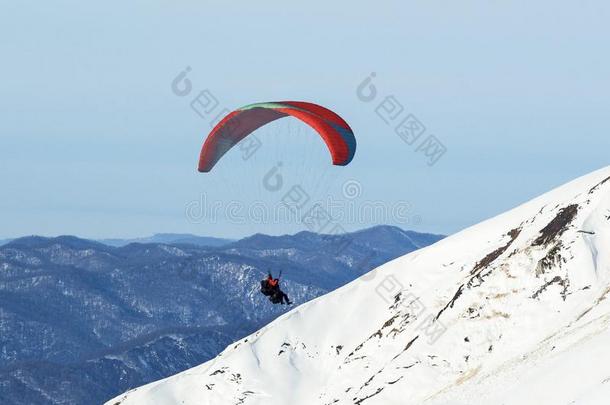 人滑翔伞运动在冬下雪的山背景