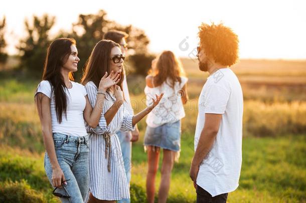 两个年幼的黑暗的-有毛发的女人闲谈和年幼的有卷发的男人太棒了