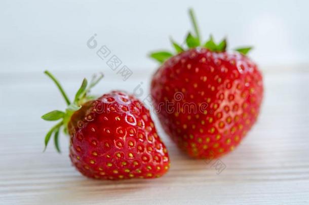 两个草莓向白色的木制的表