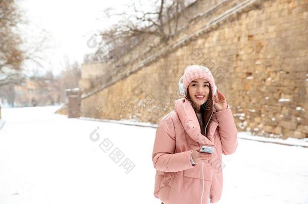 美丽的年幼的女人收听的向音乐和耳机户外的