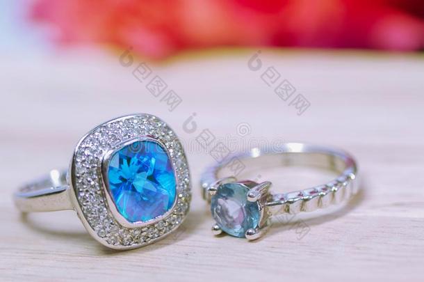 两个蓝色经雕琢的宝石戒指放置向美丽的木制的底自然