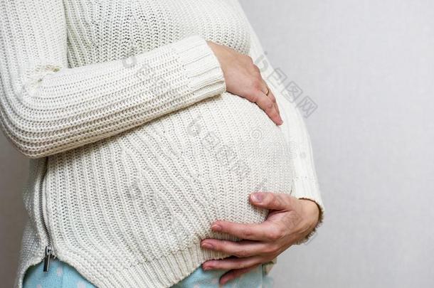 怀孕的女人保存手向肚子向光背景.孕妇