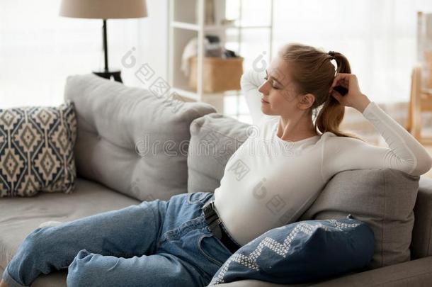 轻松的年幼的女人静止的向舒适的长沙发椅令人轻松的呼吸