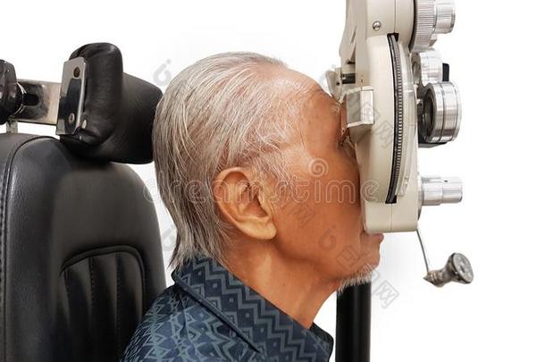 老的男人仔细检查他的眼睛在旁边使用一综合屈光检查仪