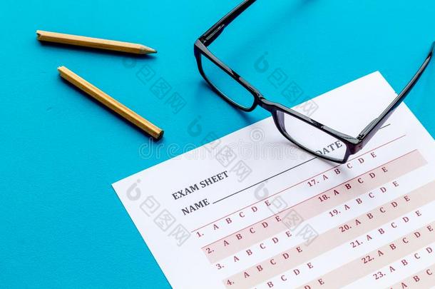 拿指已提到的人考试.考试纸在近处眼镜和铅笔向蓝色后面