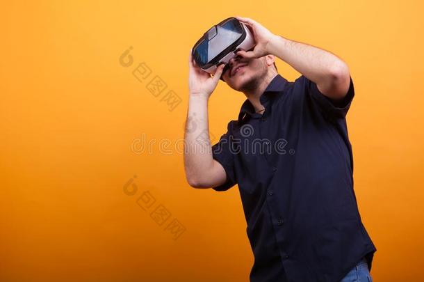 年幼的男人采用偶然的蓝色衬衫和VirtualReality虚拟现实护目镜越过黄色的后面