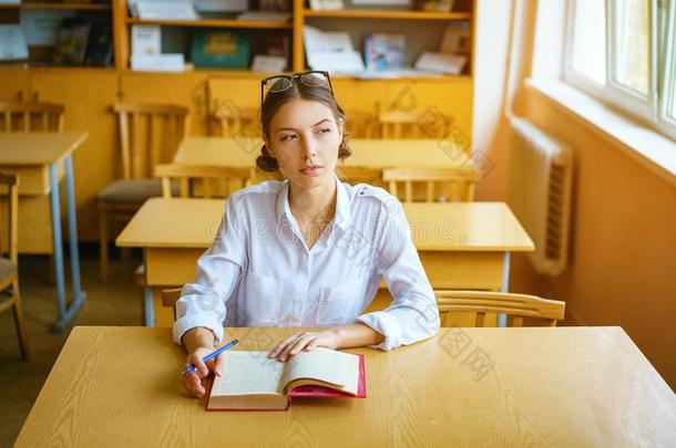 一年幼的女人一次在一书桌采用一白色的衬衫,一书向指已提到的人