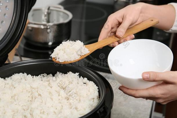 女人放置喝醉的稻进入中碗从炊具采用厨房