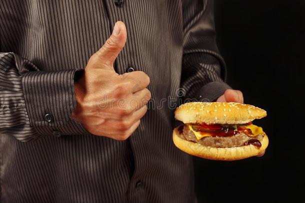 男人采用黑的衬衫托和爱好大的汉堡包向黑的英语字母表的第2个字母