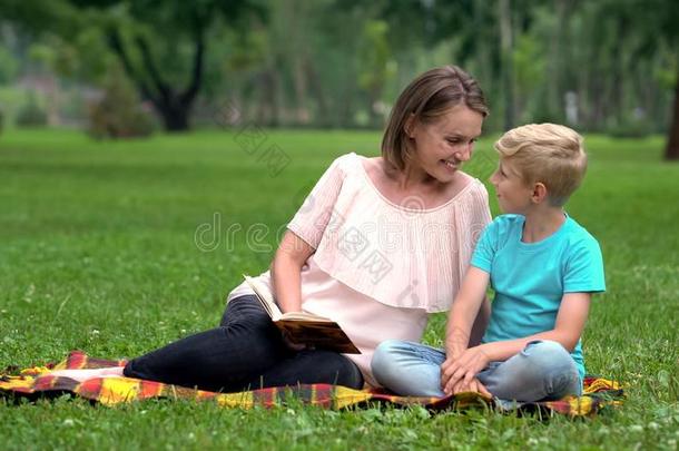 儿子和母亲阅读令人感兴趣的冒险活动书,一次向balls球