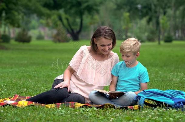 幸福的母亲和儿子阅读书在户外,普通的兴趣,花环