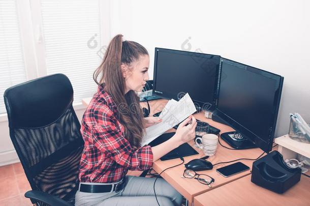 年幼的女人工作的在她<strong>书桌</strong>和<strong>书桌</strong>top计算机和纪录片