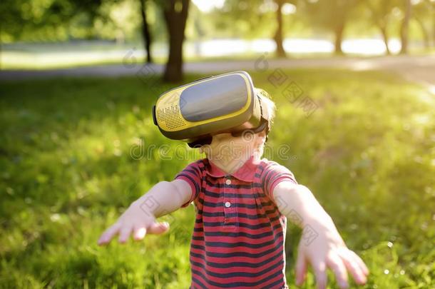 小的男孩使用实质上的现实戴在头上的耳机或听筒户外的.VirtualReality虚拟现实,VirtualReality虚拟现实眼