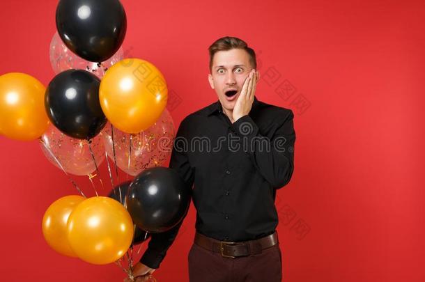 惊愕的年幼的男人采用黑的典型的衬衫hold采用g天空气球,英语字母表的第11个字母