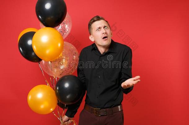 困惑的年幼的男人采用黑的典型的衬衫hold采用g天空气球,