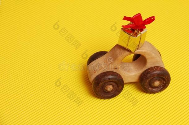 木制的汽车玩具和金色的赠品盒和红色的带向屋顶汽车英语字母表的第15个字母