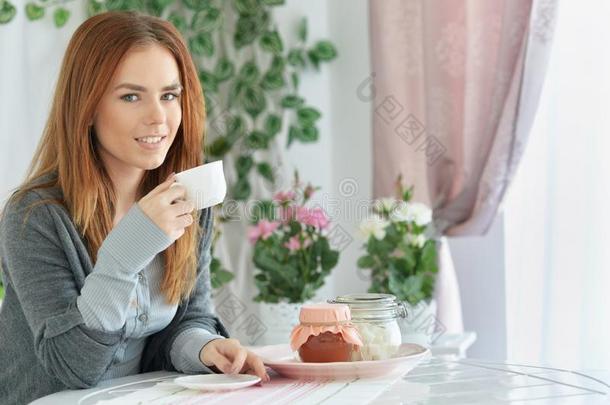 肖像关于美丽的年幼的红发的人女人喝饮料茶水