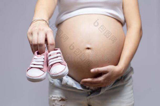关-在上面关于怀孕的女人和<strong>婴儿鞋</strong>子向她肚子