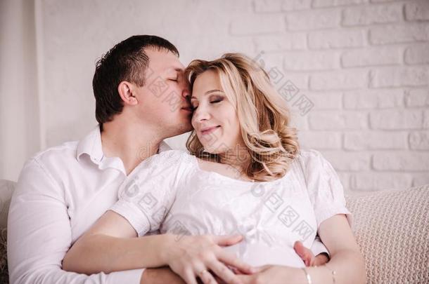 幸福的丈夫接吻的他的怀孕的妻子幸福的.