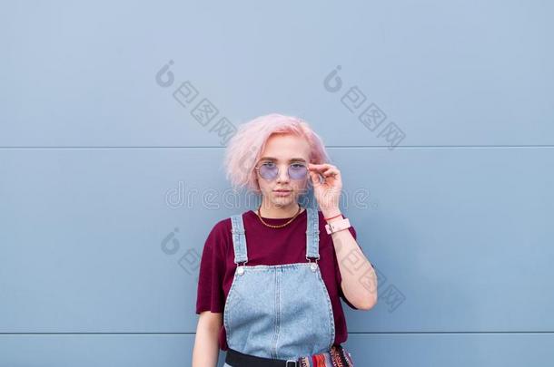 时髦的女孩和粉红色的头发和太阳镜是（be的三单形式一蓝色b一ckground