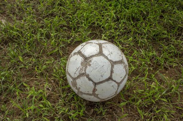 白色的老的破旧的足球球向变模糊绿色的草
