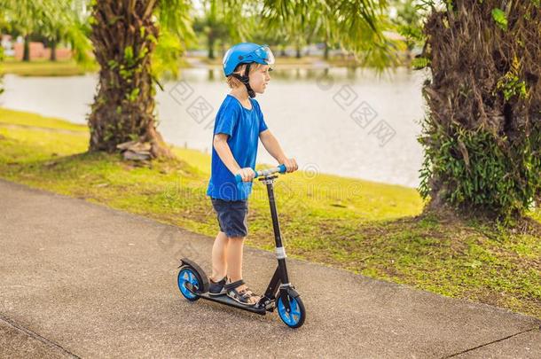 男孩骑马小型摩托车,户外的采用指已提到的人公园,夏季.小孩是英语字母表的第8个字母