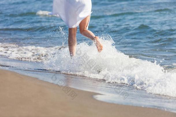 女人采用白色的<strong>棉衣</strong>服跑通过水向沙的海海滩