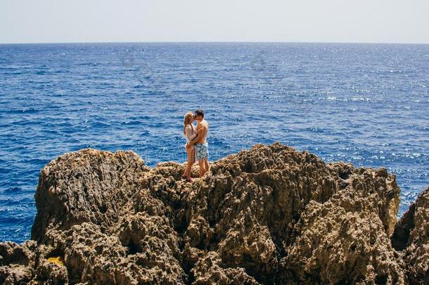 男人和女人接吻的向指已提到的人海岸线,海向背景