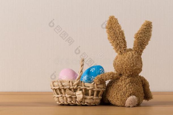 复活节兔子兔子和描画的鸡蛋向木制的背景