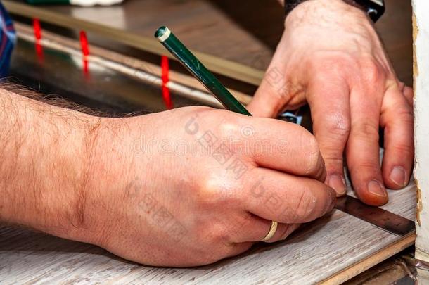 男人使用量肘部和铅笔在期间安装新的木制的