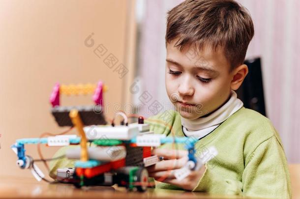 勤奋的男孩打扮好的采用绿色的毛衣坐在指已提到的人书桌和比较两个或多个文件