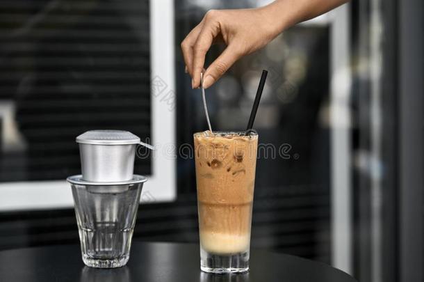女人移动冰冷的咖啡豆喝和勺采用户外的咖啡馆