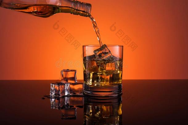 威士忌酒乙醇传布进入中玻璃和冰喝向桔子后面