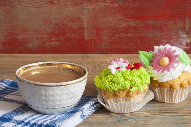 花春季纸杯蛋糕和热的咖啡豆杯子向木制的表