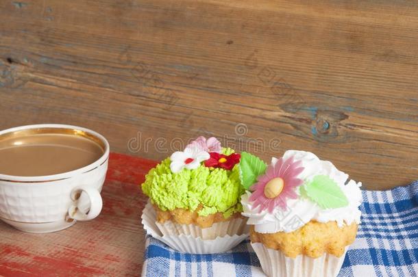 花春季纸杯蛋糕和热的咖啡豆杯子向木制的表