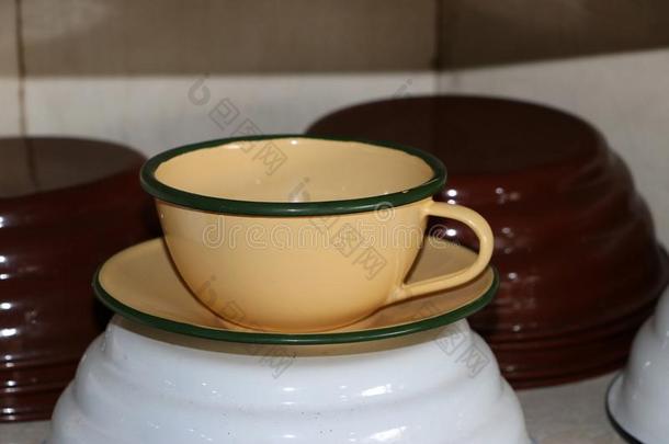 锌杯子和茶杯托采用乳霜-有色的.它是（be的三单形式古老的杯子