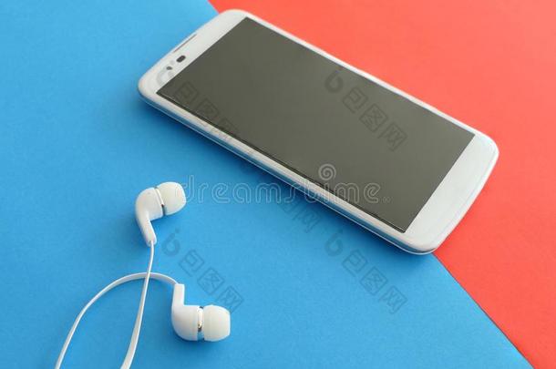 白色的智能手机和耳机向一红色的和蓝色B一ckground